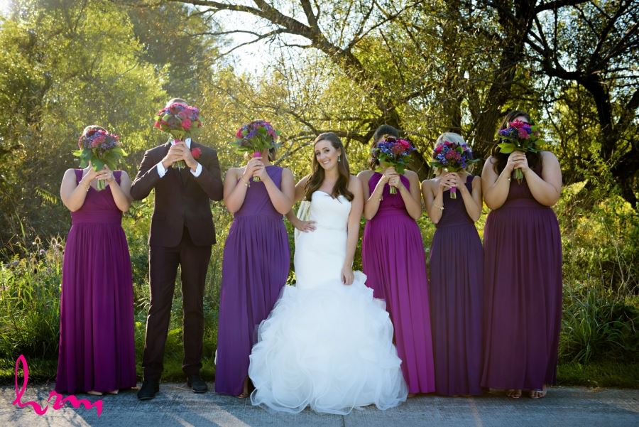 bride and bridesmaids holding flowers in front of faces