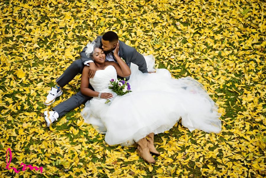 bride and groom on ground with autumn leaves