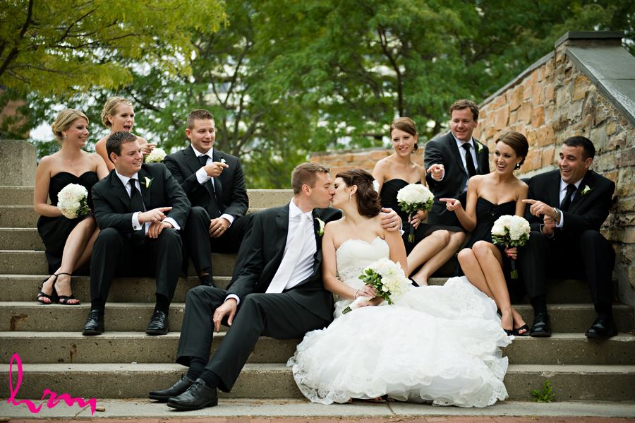 wedding party on stairs and bride and groom kissing