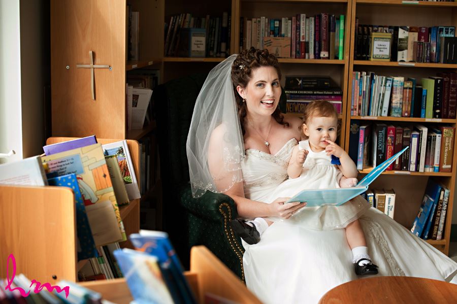 bride reading a book with flower girl before ceremony