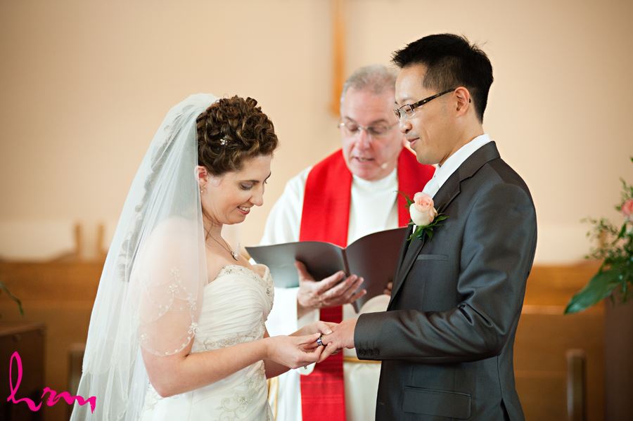 bride placing ring on grooms finger in church