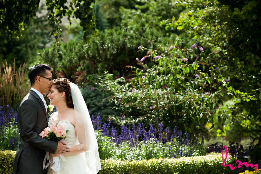 groom kissing bride on forehead in flowers