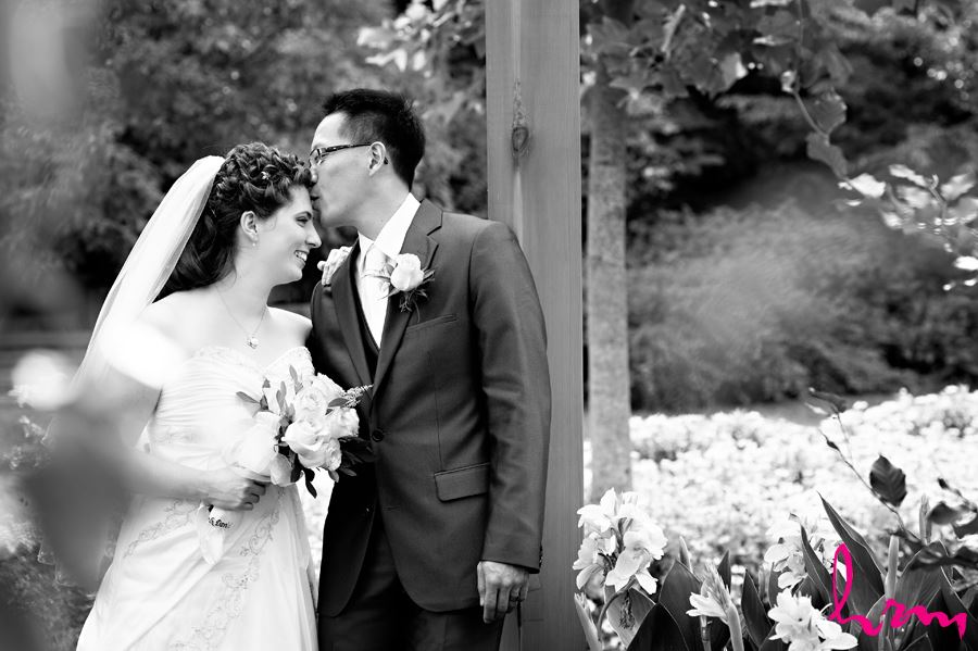 black and white groom kissing bride on head
