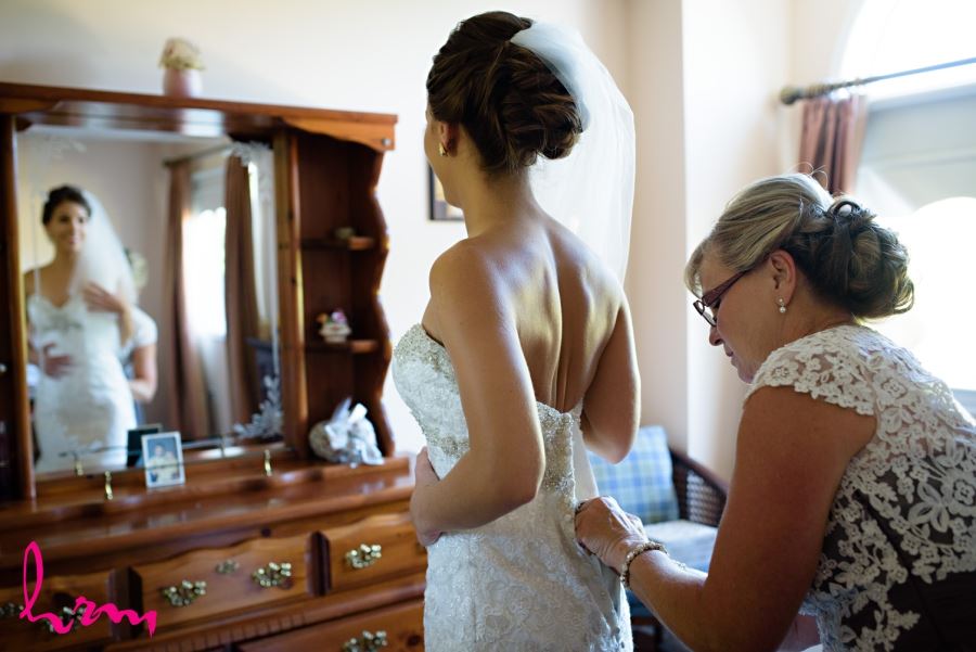 bride and mother putting on wedding dress