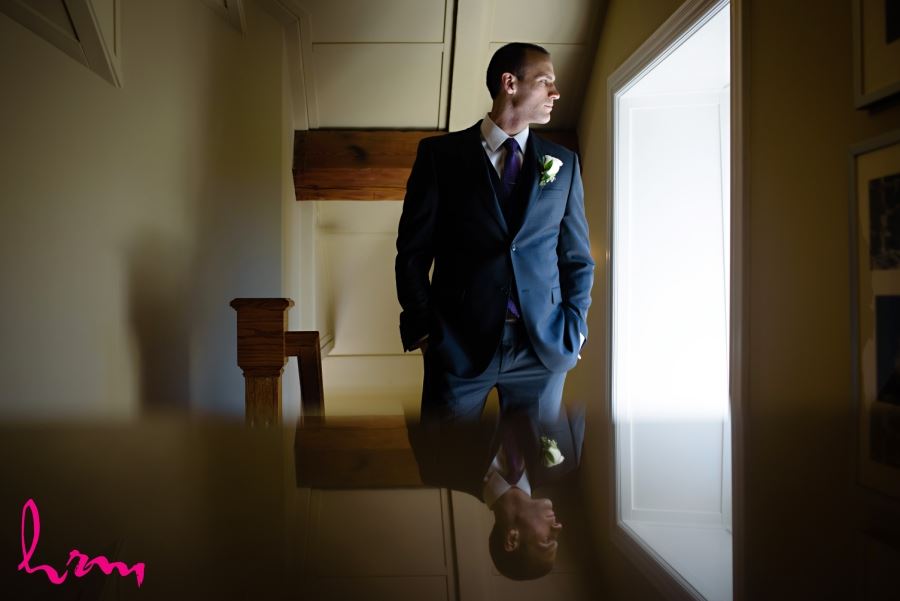 groom standing in front of window