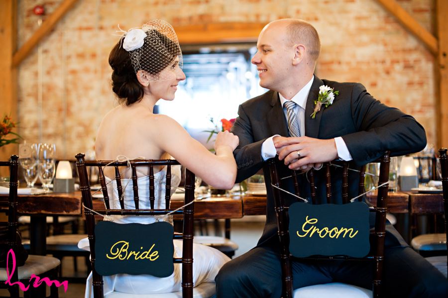 bride and groom sitting in archeo with bride and groom signs