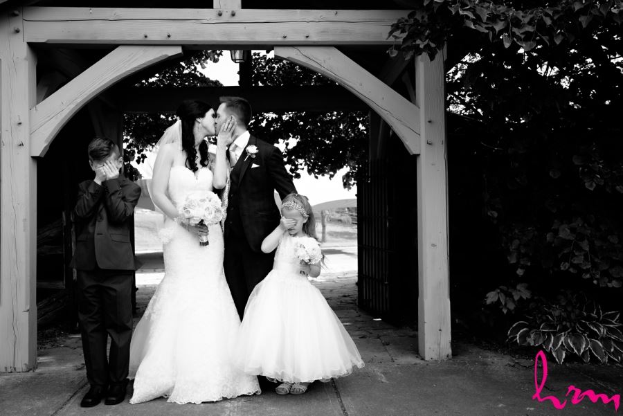 bride and groom kissing with ring bearer and flower girl