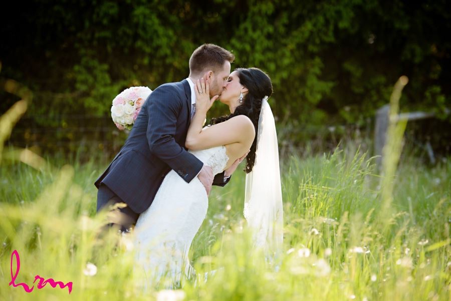 bride and groom kissing in field 