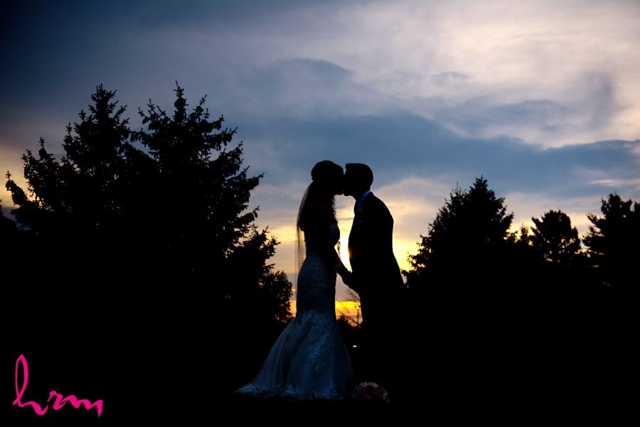 bride and groom kissing during sunset