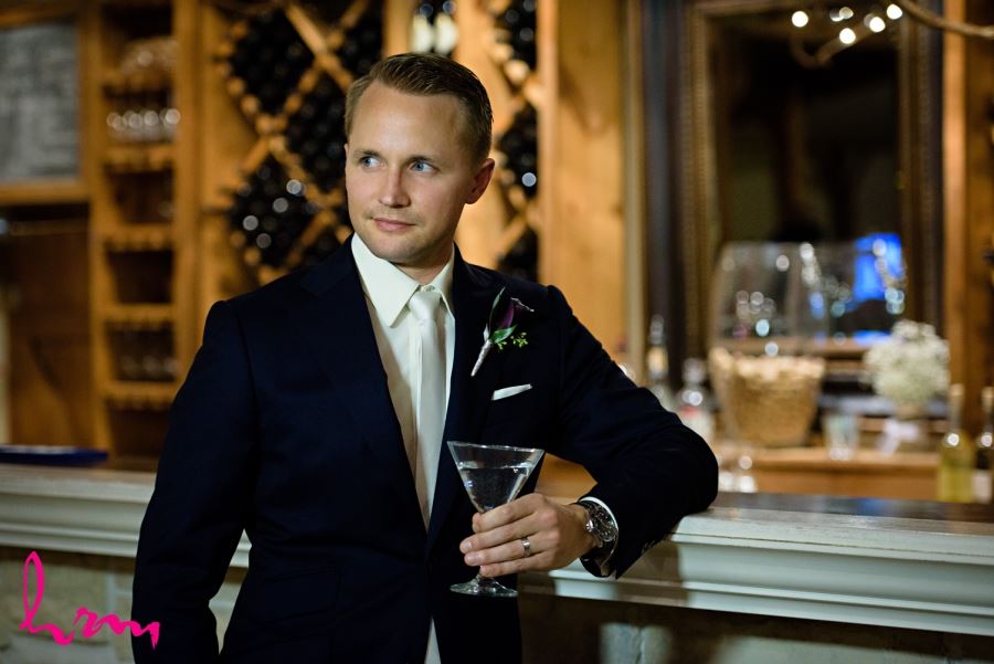 groom leaning on bar with drink