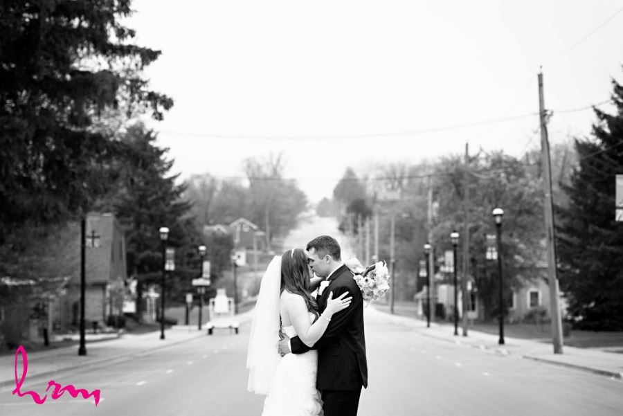 bride and groom kissing in street black and white