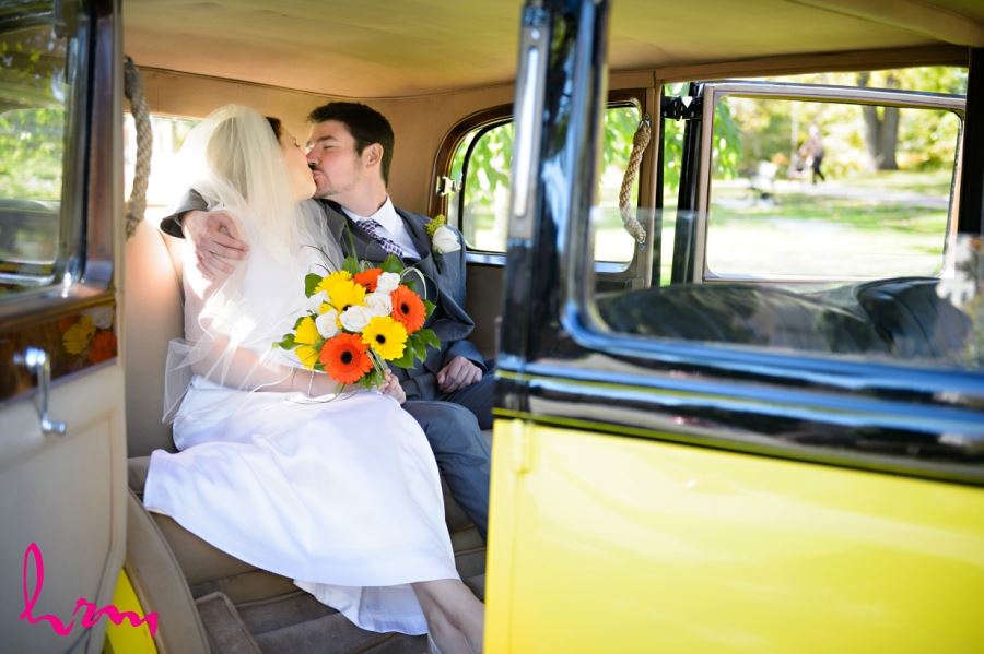 bride and groom kissing in backseat of car