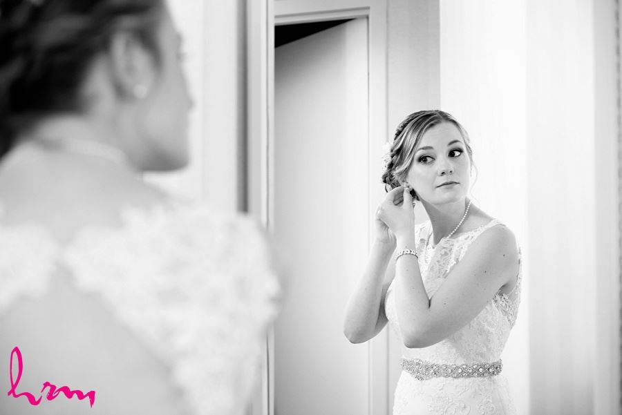 Black and white photo of bride putting in earrings taken by London Ontario wedding photographer