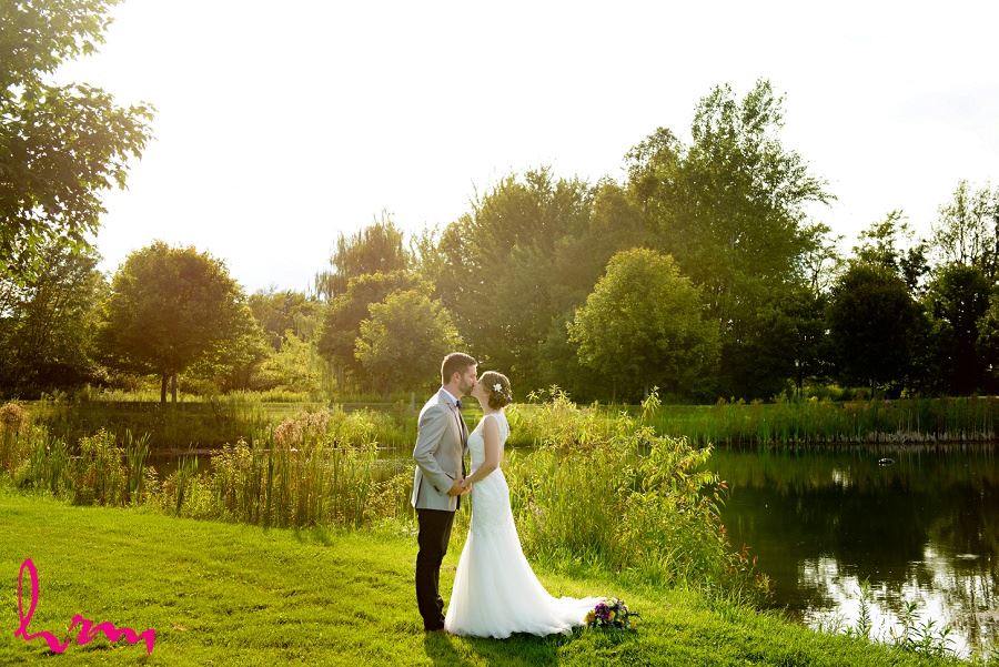 Photo of bride and groom by pond by London Ontario Wedding Photographer 
