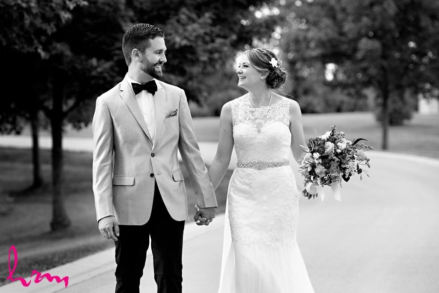 Black and white photo of bride and groom walking down road by London Ontario Wedding Photographer 
