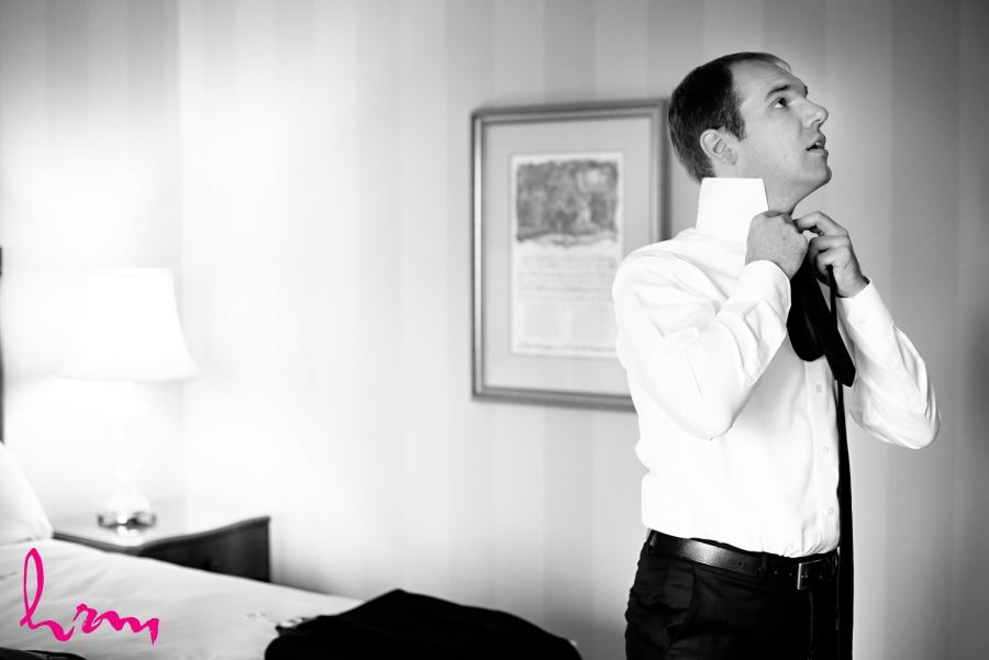 groom tying tie on wedding day black and white