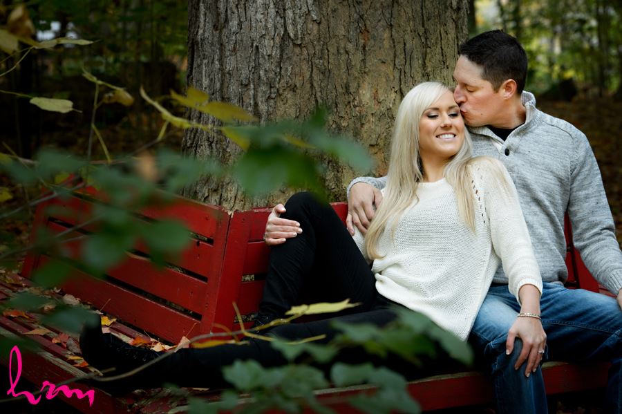 Couple kissing on red bench in the forest in London Ontario
