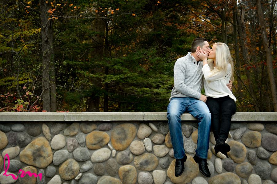 Engaged couple kissing on stone wall