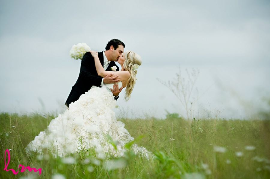 Wedding photo of bride and groom kissing in a field