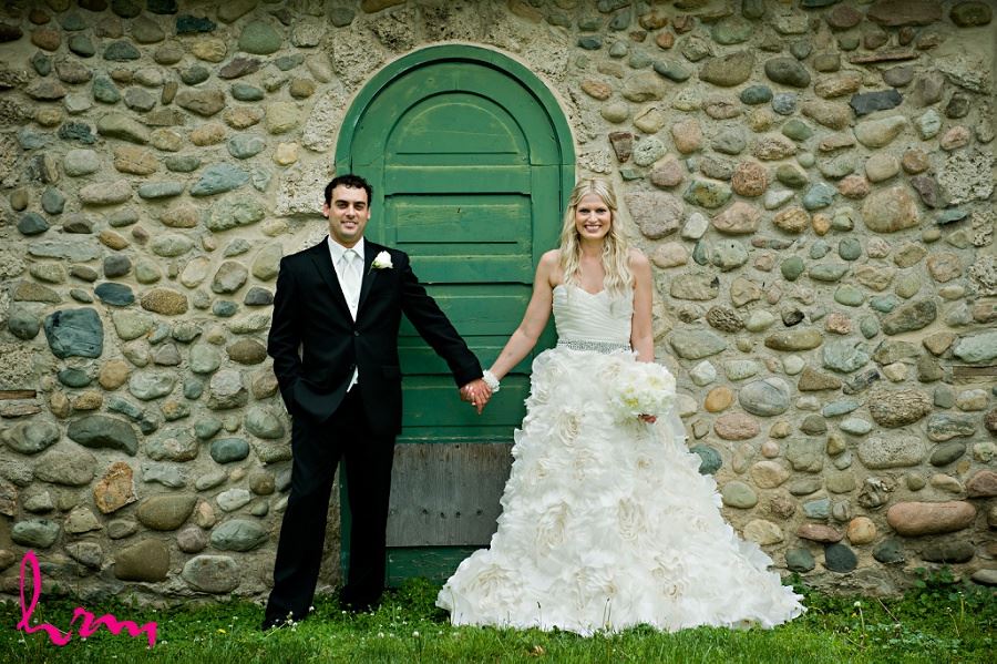 Wedding photograph of bride and groom in front of stone wall