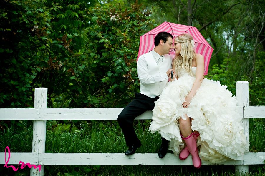 Wedding photo of bride and groom sitting on fence