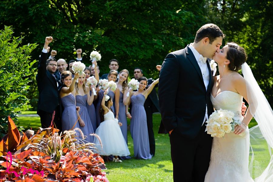 bride and groom kissing in front of wedding party