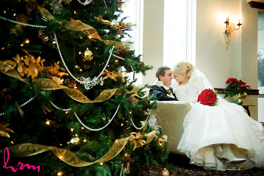 bride and groom sitting by christmas tree