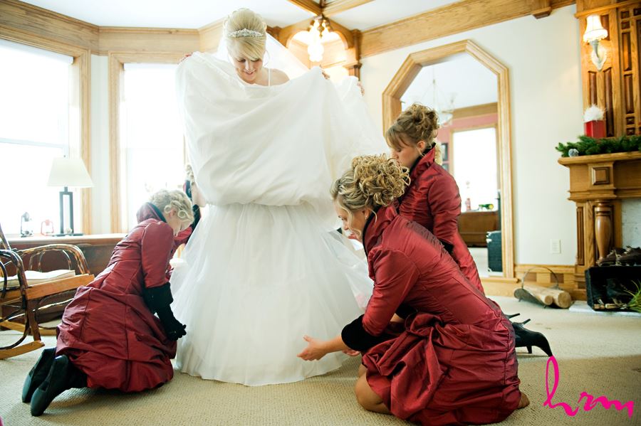 bridemaids helping bride get dressed at brides house