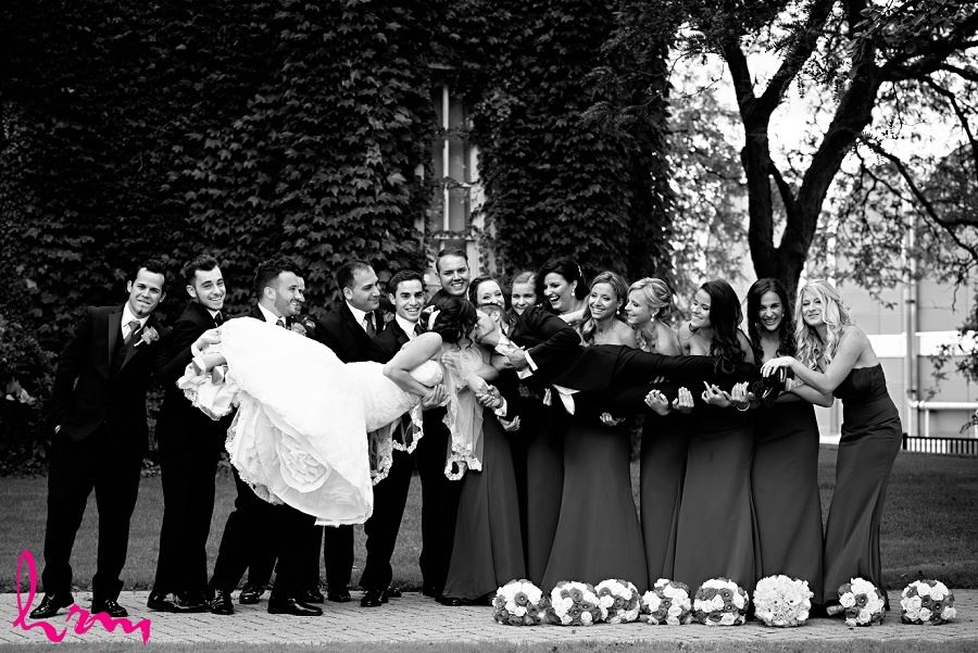 fun wedding day photo idea with wedding party and bride and groom kissing