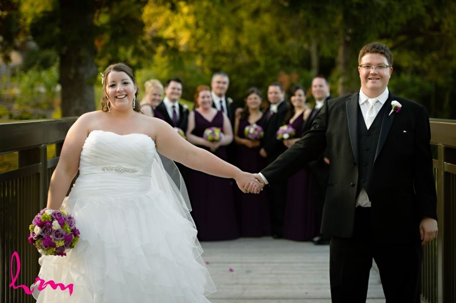 bride and groom holding hands in front of wedding party