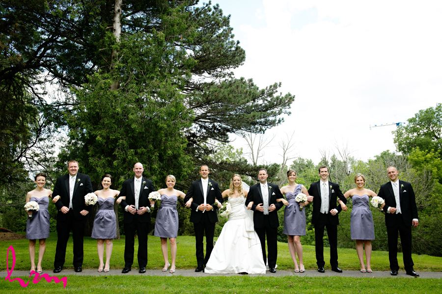 Unique photo of wedding party all linking arms wearing purple in London Ontario