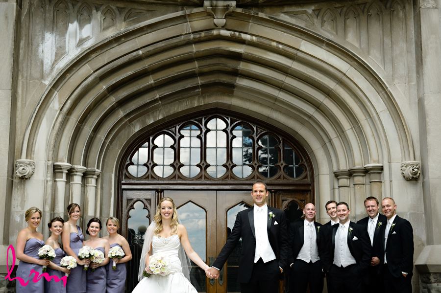 Bride and Groom with their bridal party in front of arch doorway infront of University College at Western University