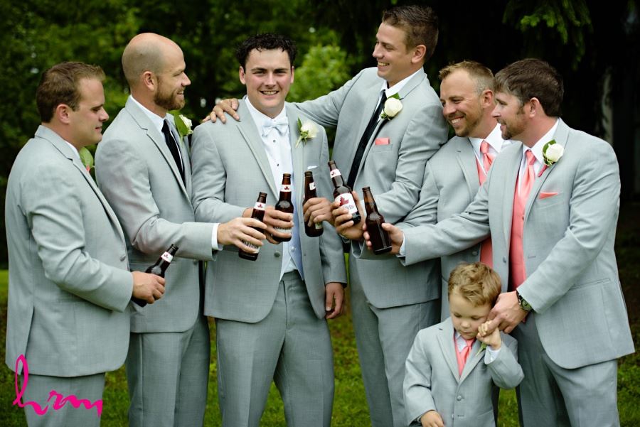 Groom and groomsmen in gray suits and coral vests and ties